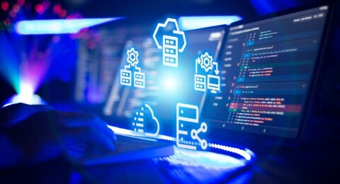 Developer typing near monitors showing code and glowing cloud data storage icons.